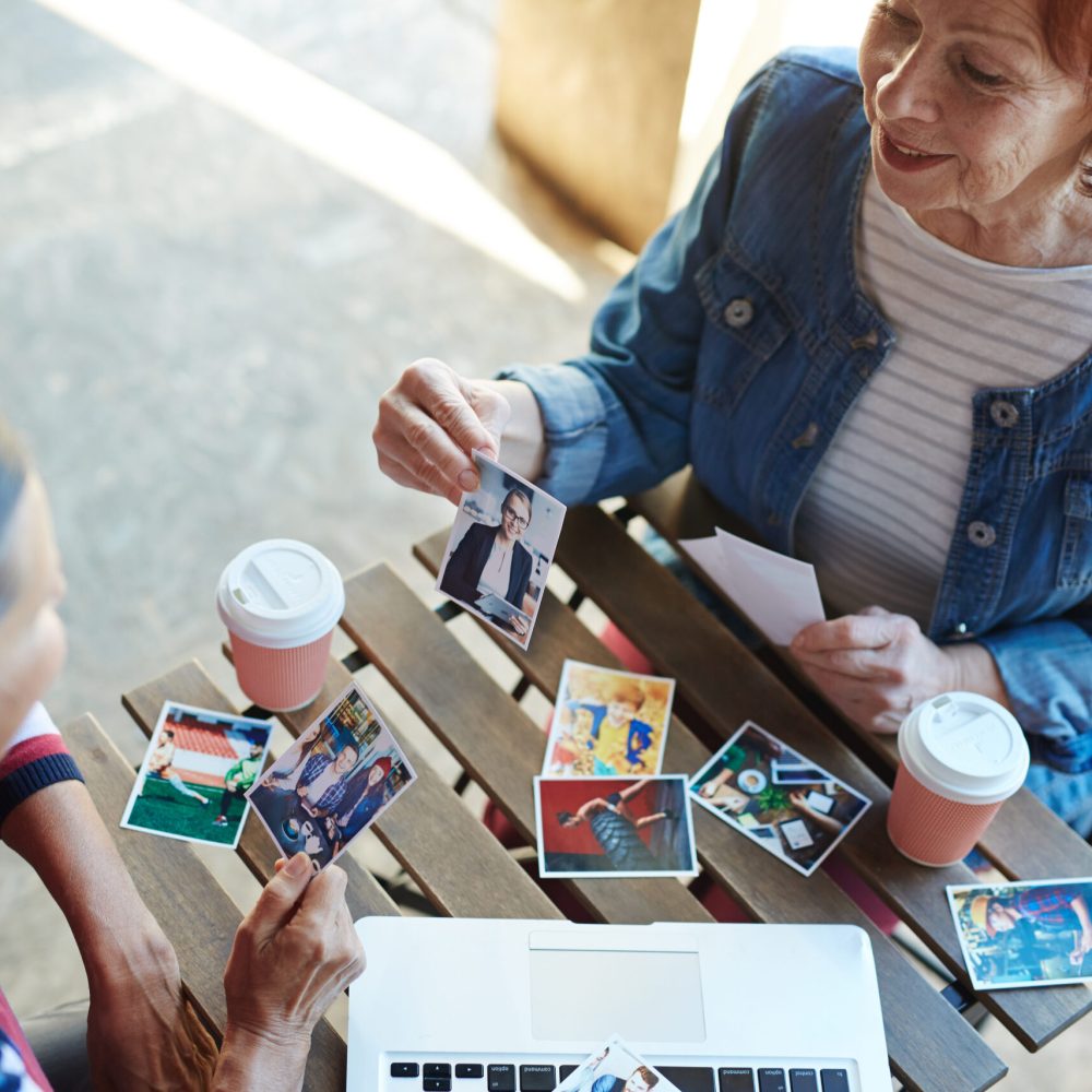 Two senior buddies looking through photos of their relatives